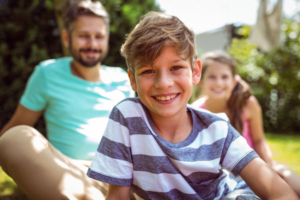 boy sitting with family in their yard